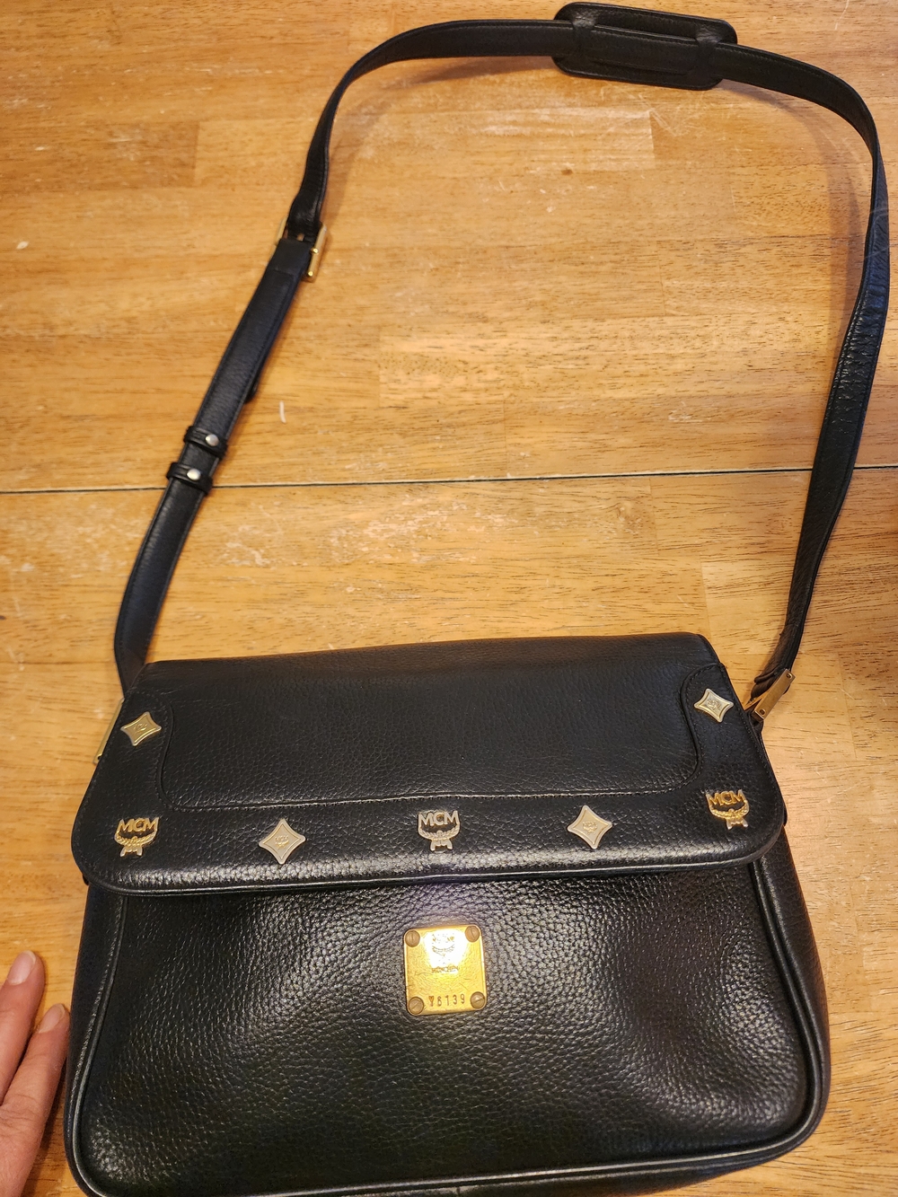 vintage MCM black pebbled leather studded crossbody bag featuring a front plaque
